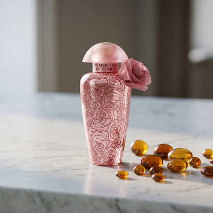 The Merchant of Venice La Fenice Rosa Monceniga Elixir EDP on cream stone with a scatter of honey-colored ambergris flakes