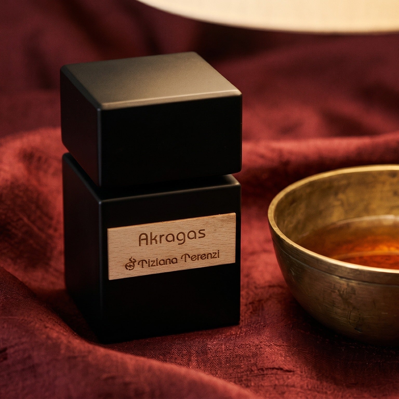Tiziana Terenzi Akragas EDP on raw silk of oxblood color with a brass bowl of ambergris tincture
