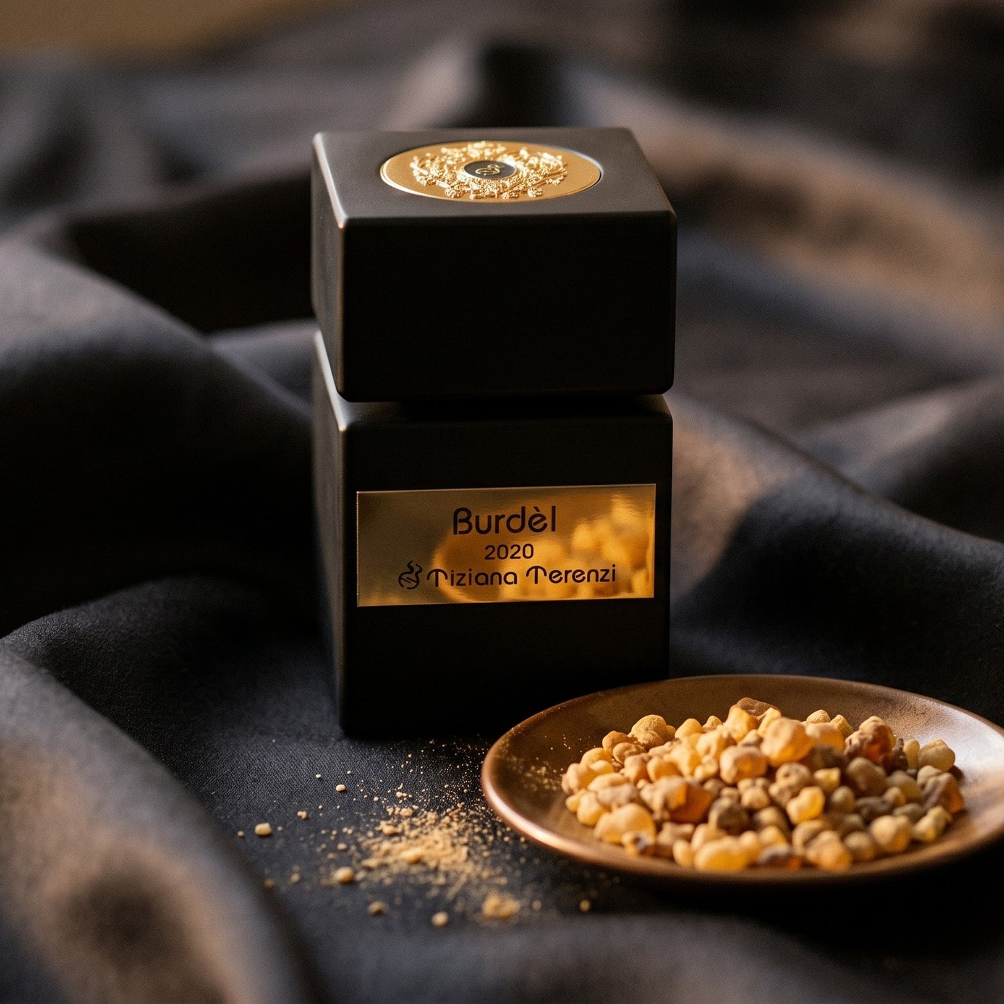 Tiziana Terenzi Burdel EDP on burnt-orange silk with smoldering agarwood on a stone dish