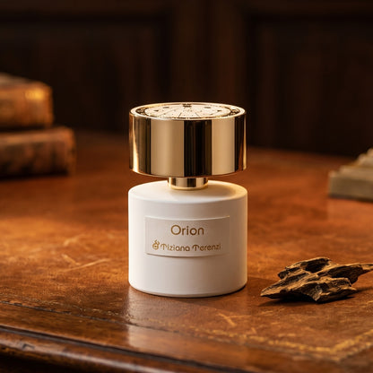 Tiziana Terenzi Orion EDP on dark tan leather desk with a brass lamp casting a warm pool of light
