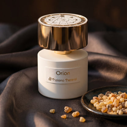 Tiziana Terenzi Orion EDP on burnt-orange silk with smoldering agarwood on a stone dish