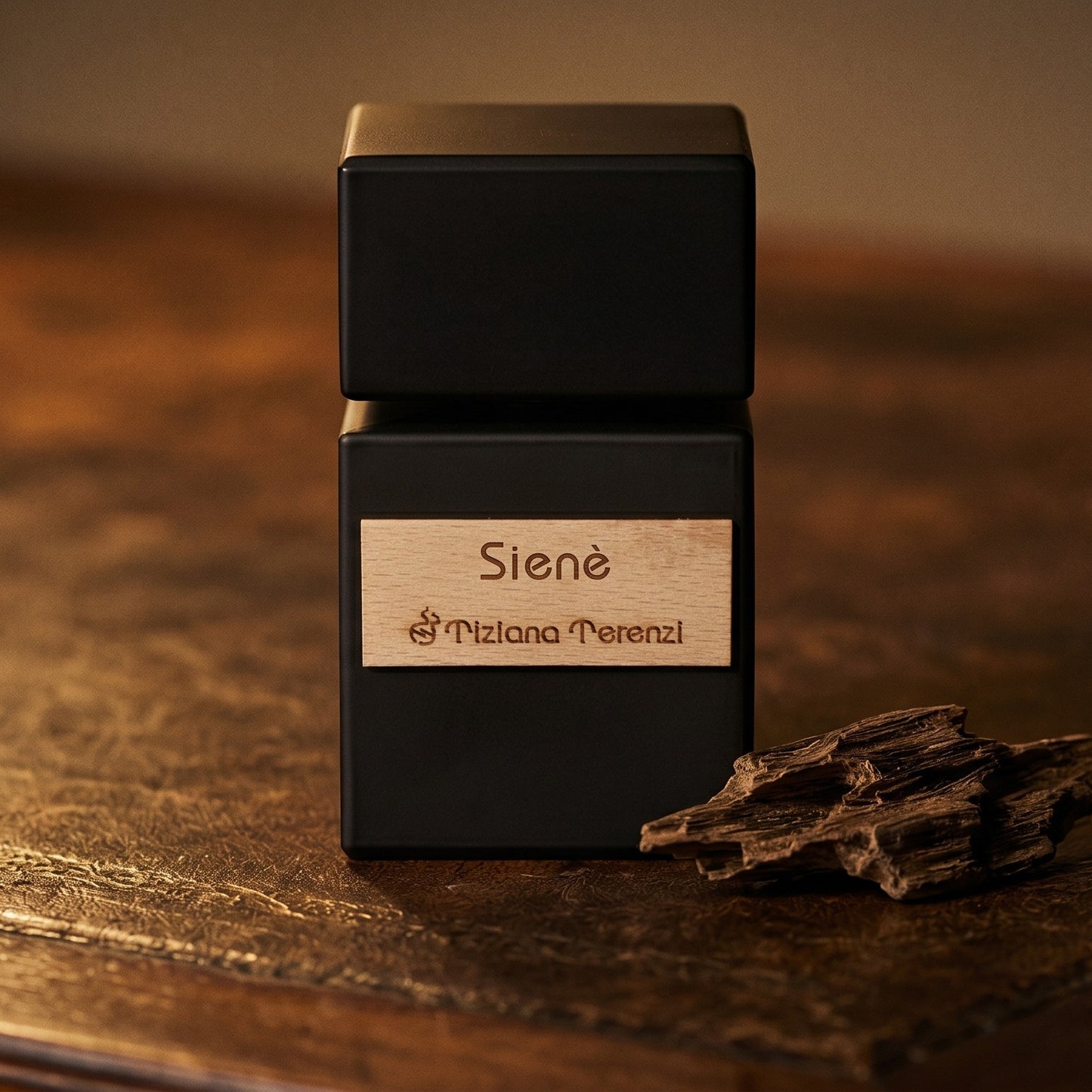 Tiziana Terenzi Siene EDP on cognac leather bench with a curled strip of birch bark nearby