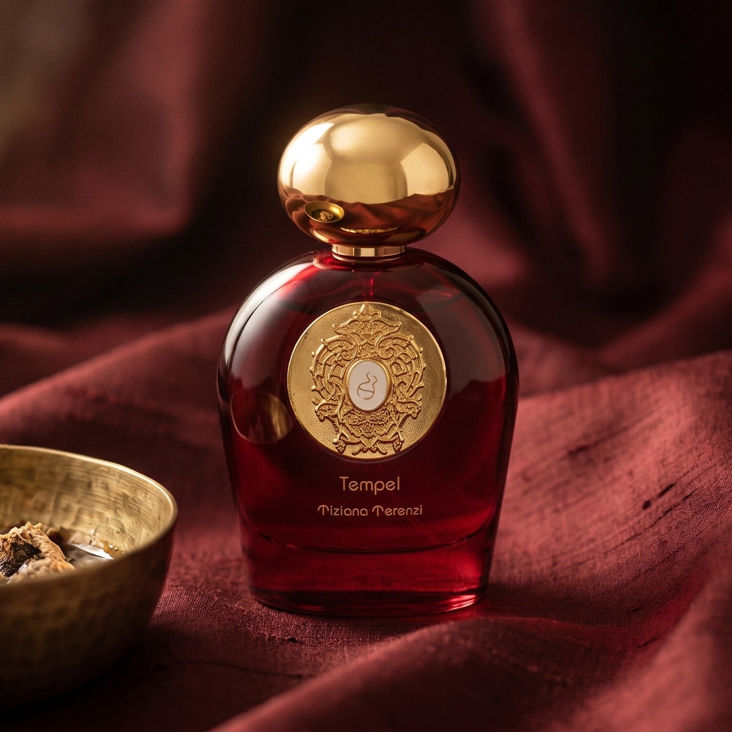 Tiziana Terenzi Tempel Comete EDP on cinnamon-tone silk with a shallow saucer of warm benzoin resin