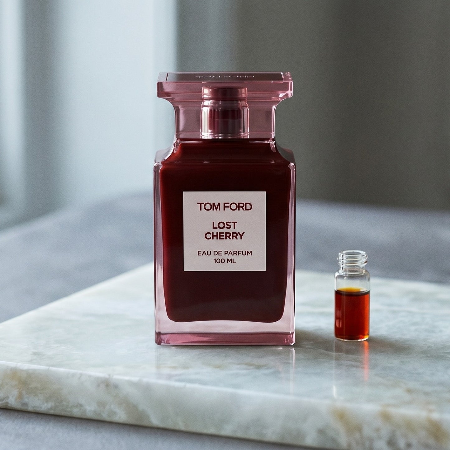 Tom Ford Lost Cherry on cream-toned stone with a glass pipette of rose absolute