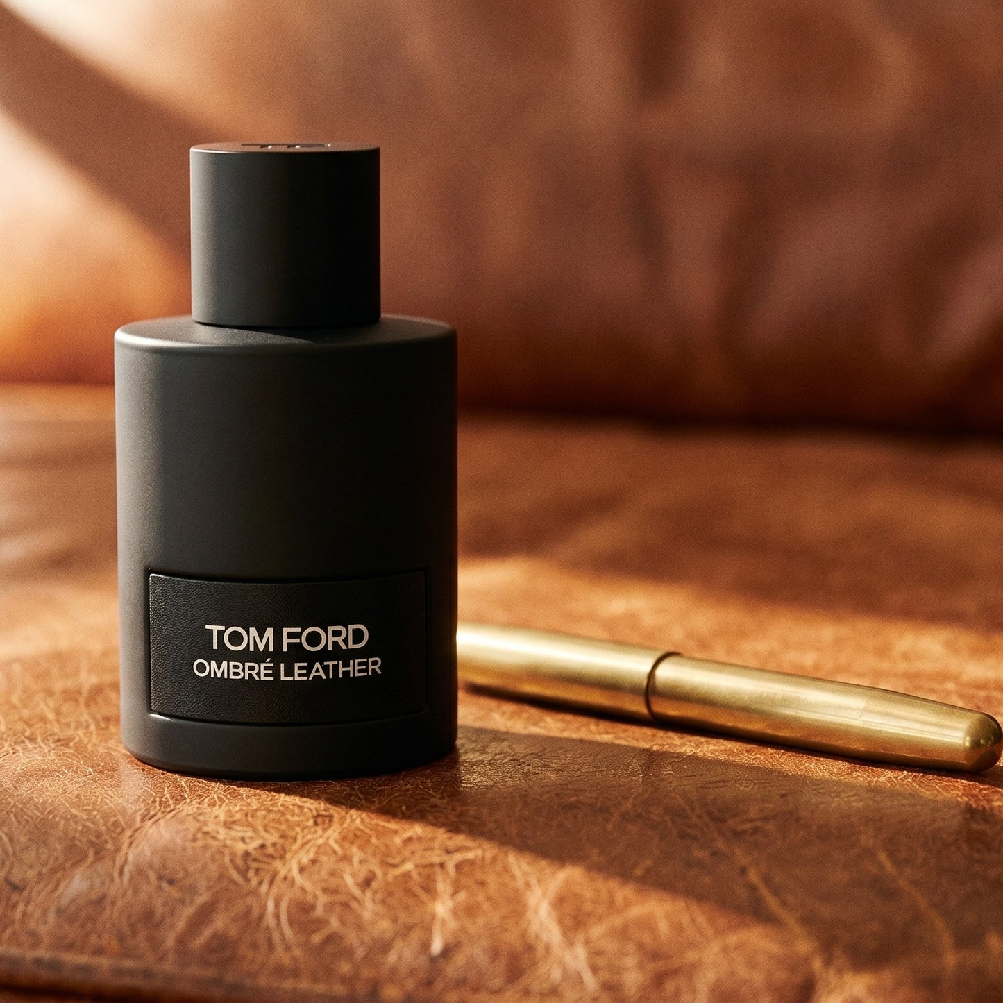 Tom Ford Ombre Leather EDP on worn tobacco leather desk with a leather-bound notebook lying open