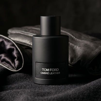 Tom Ford Ombre Leather EDP on black suede surface with a folded pocket square beside the base