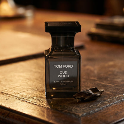 Tom Ford Oud Wood on aged leather-topped desk with a single agarwood chip beside the bottle