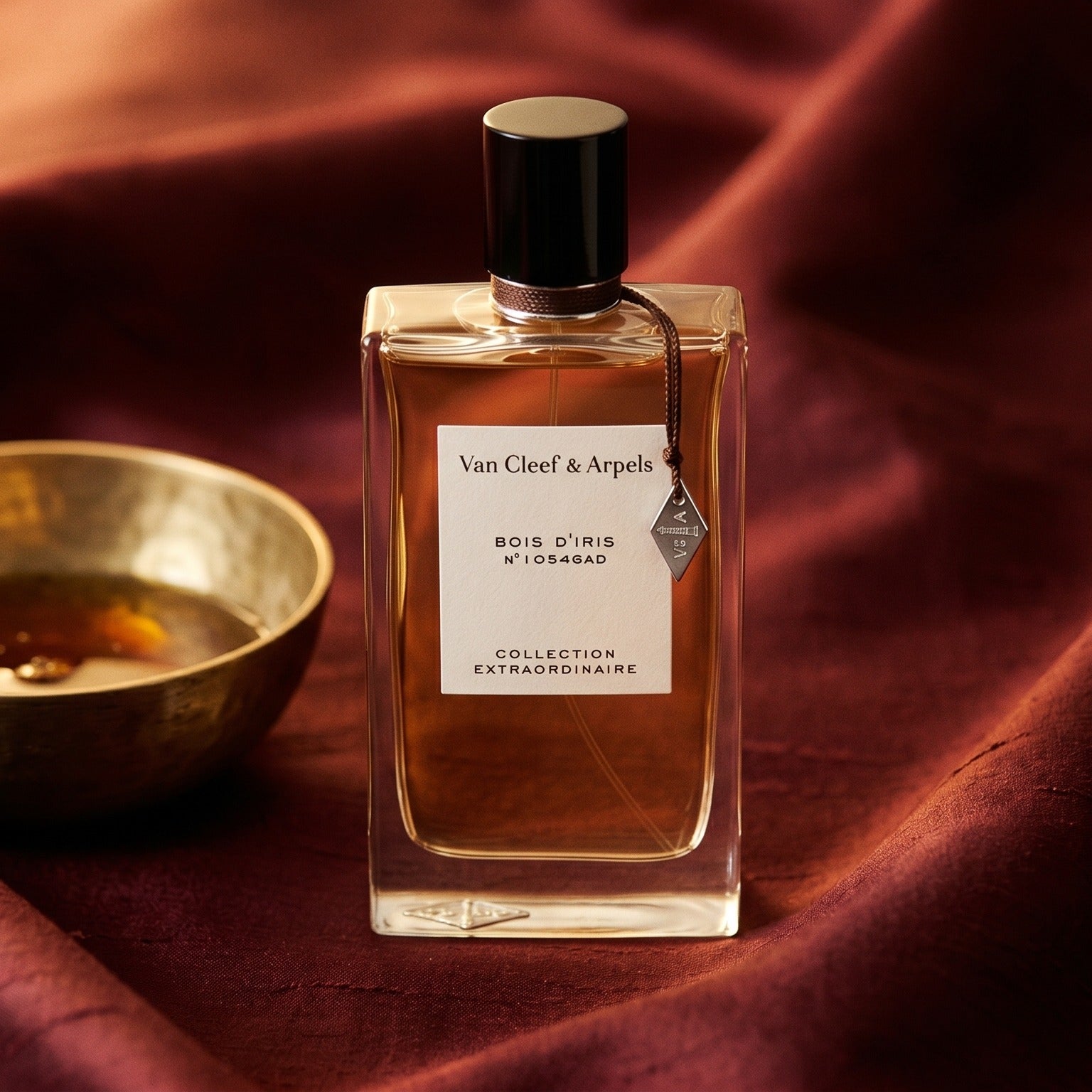 Van Cleef Bois Diris EDP on burnt-orange raw silk with a brass vial of frankincense oil