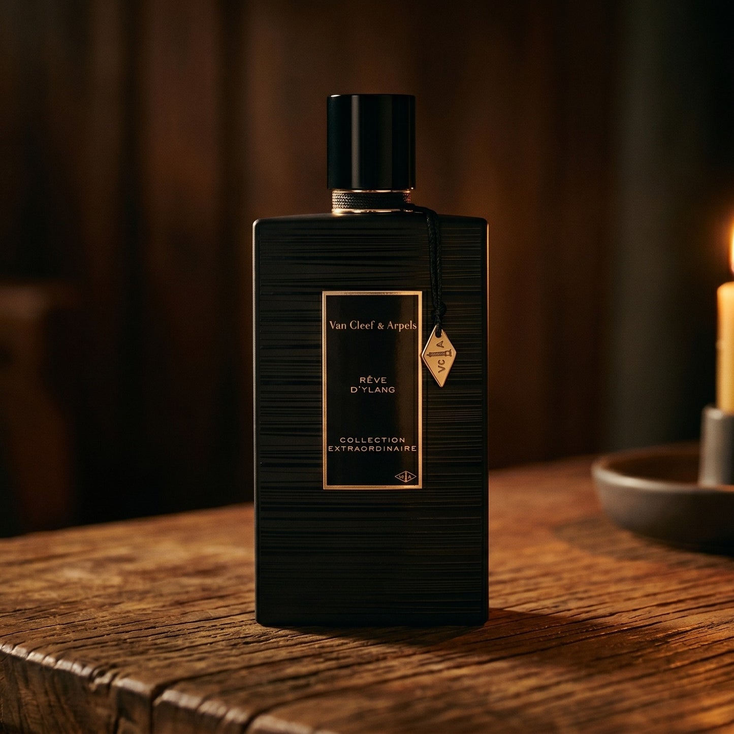 Van Cleef Reve de Ylang on walnut side table with a pair of lit votives beside the bottle