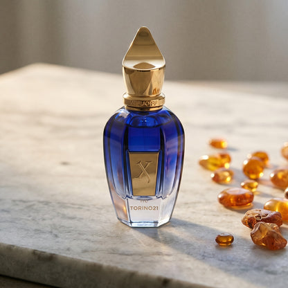 Xerjoff Torino 21 on pale grey marble with amber resin beads scattered to one side