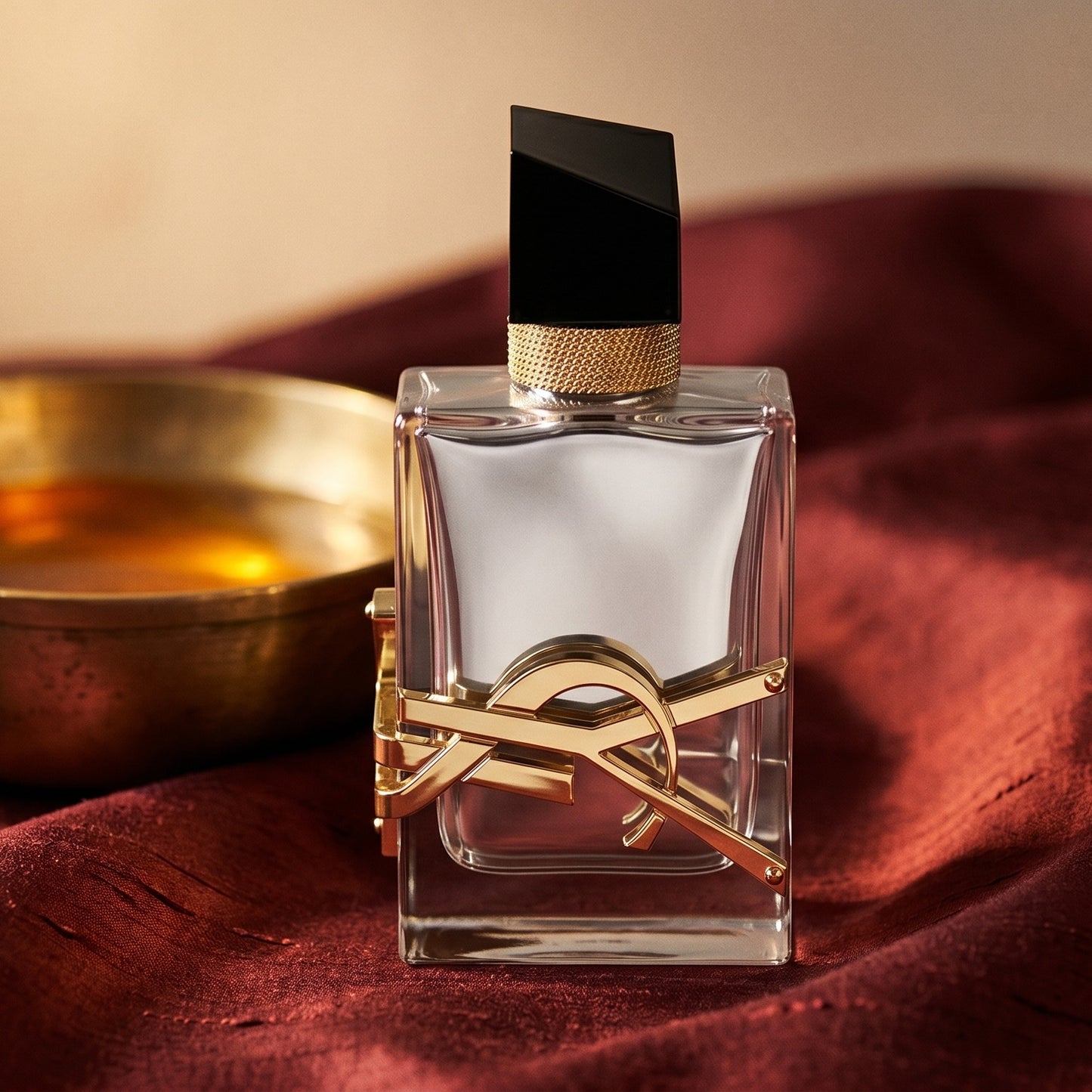 Yves Saint Laurent Libre Absolu Platine on russet silk with a matte brass bowl holding tonka and amber pieces