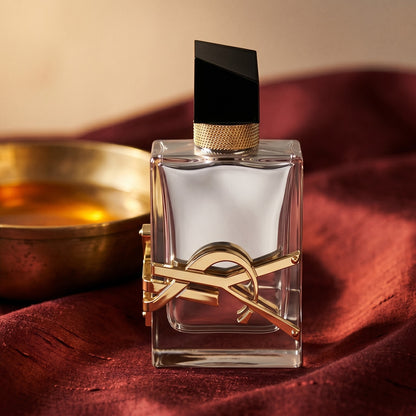 Yves Saint Laurent Libre Absolu Platine on russet silk with a matte brass bowl holding tonka and amber pieces