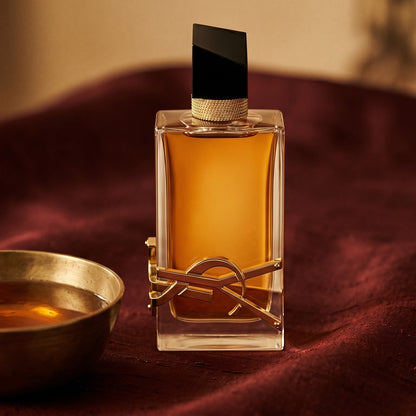 Yves Saint Laurent Libre Intense EDP on amber-toned satin with a gold-rim ceramic dish of labdanum