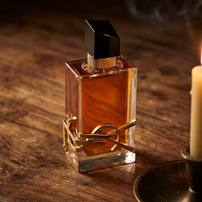Yves Saint Laurent Libre Intense EDP on aged teak with a candle burning gently to frame-right