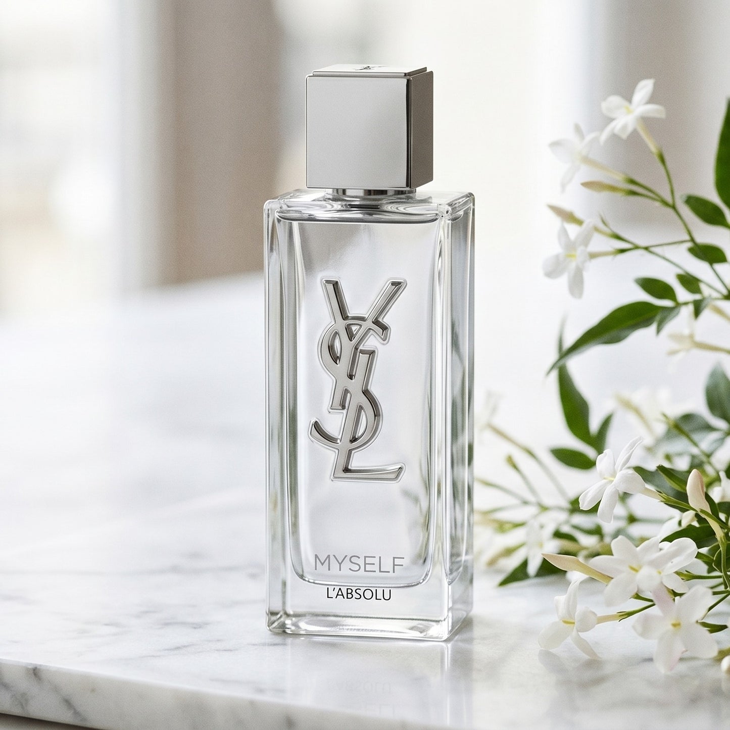 Yves Saint Laurent Myslf L Absolu Parfum on pale limestone with tuberose stems laid loosely beside the bottle