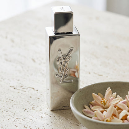 Yves Saint Laurent Myslf L Absolu Parfum on pale stone with orange-blossom petals in a shallow bowl